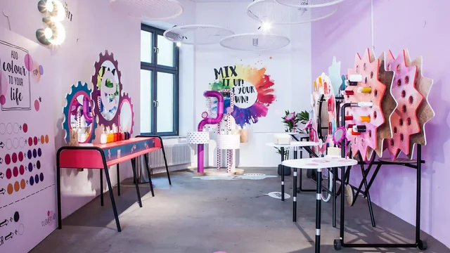 Farbenfrohe Installationen schmücken kreativen Raum mit Tischen und dekorativen Elementen