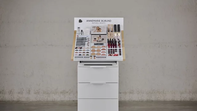 Kosmetikdisplay präsentiert Produkte auf weißem Stand vor grauer Wand