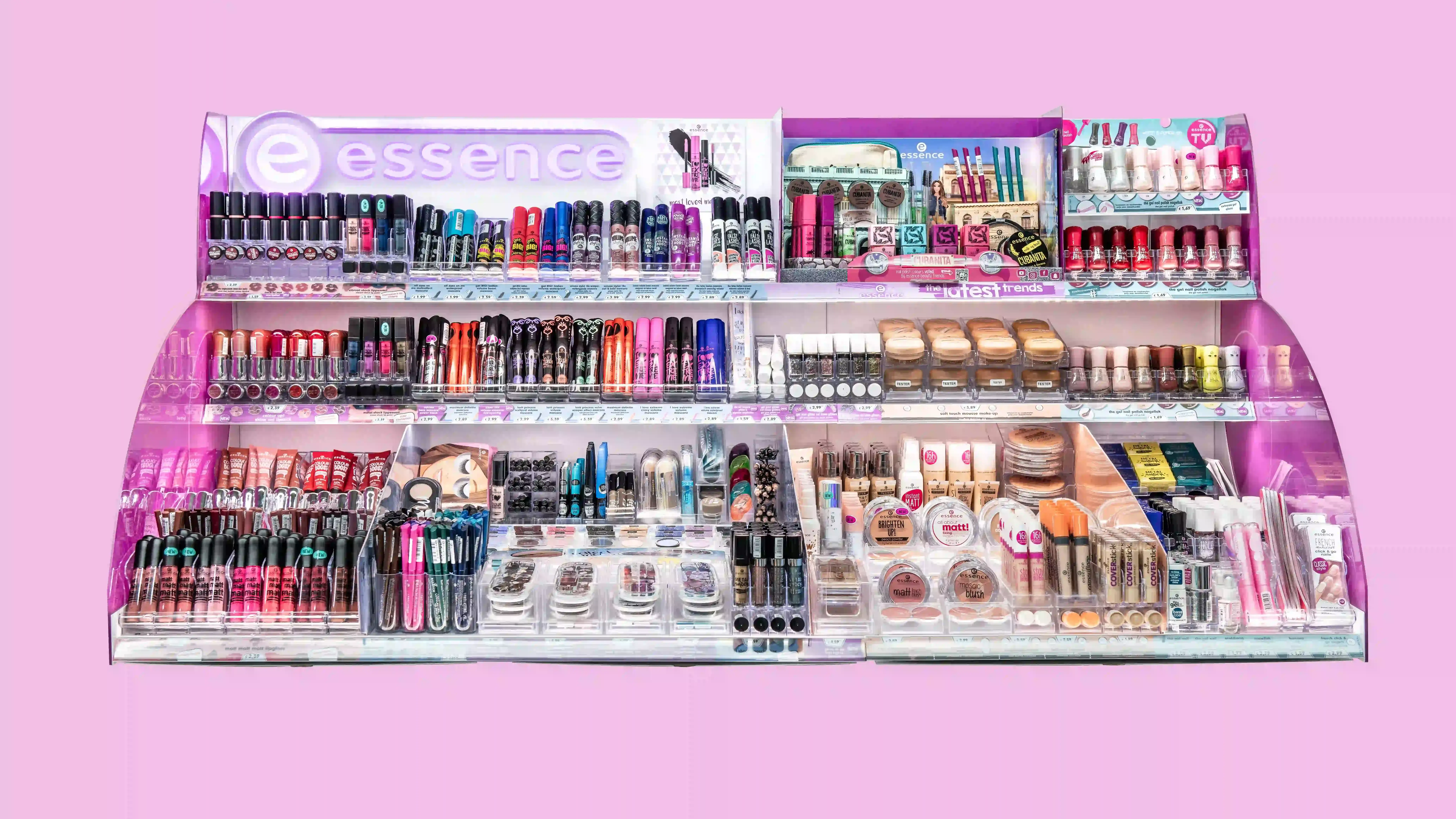 Cosmetics display showcasing diverse makeup products on pink background