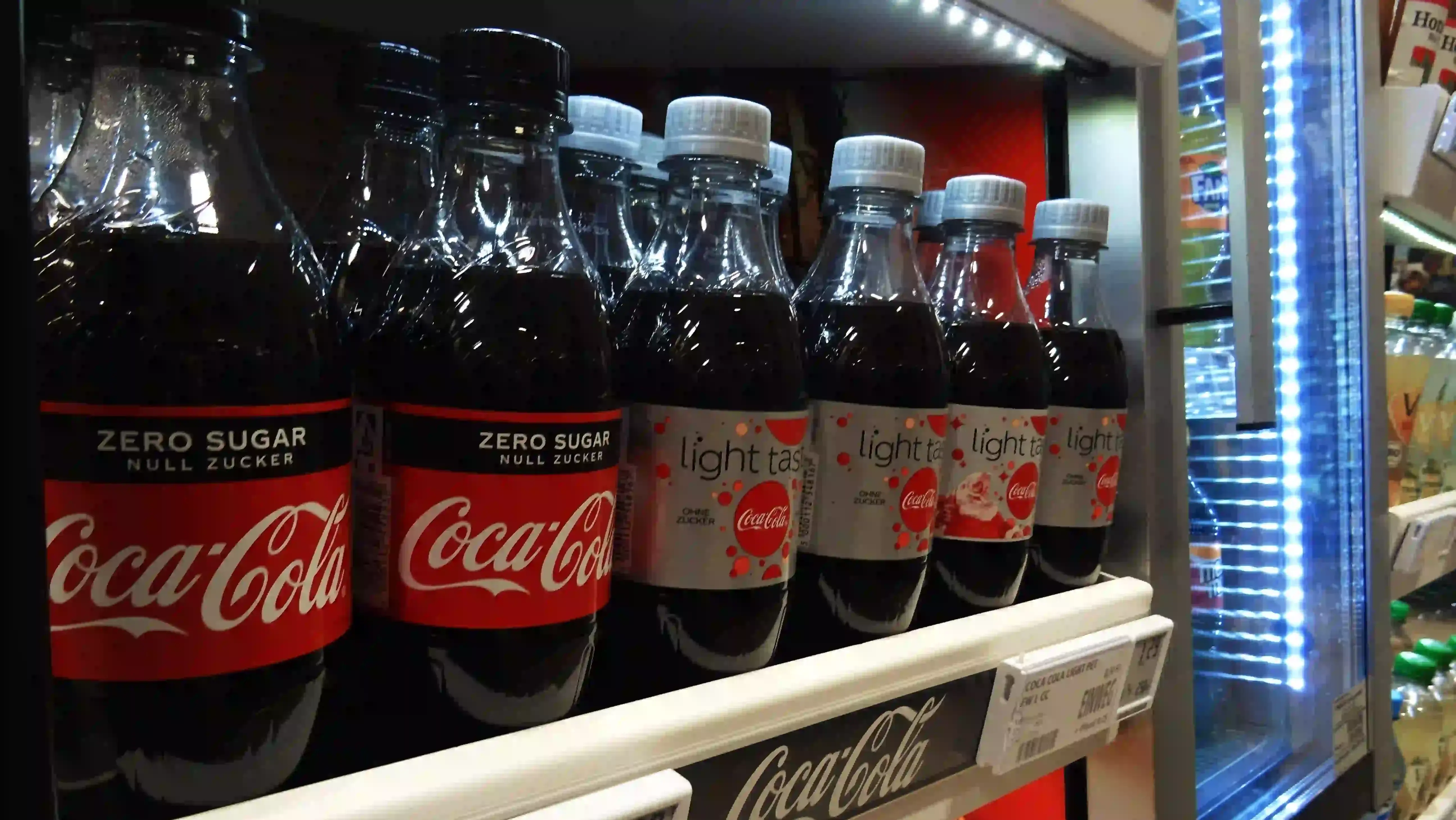 Coca-Cola bottles displayed on a shelf in a grocery store