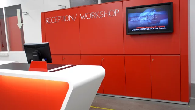 Modern reception desk sits beside red workshop unit