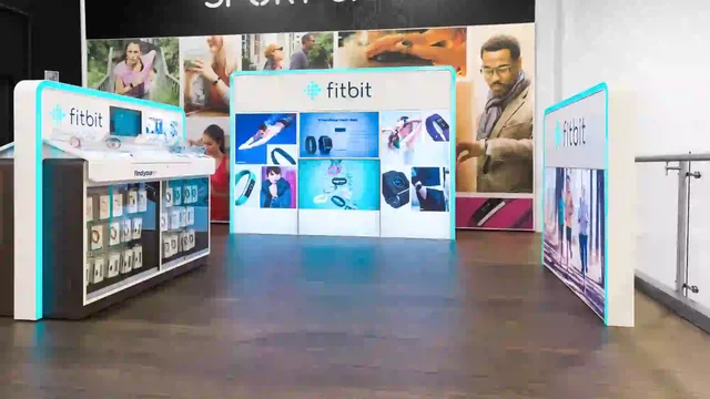 Fitbit-Display präsentiert Produkte in einem Sportgeschäft mit Werbebildern im Hintergrund