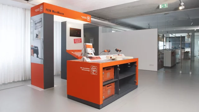Werkzeugdisplay präsentiert Produkte in modernem Ausstellungsraum mit orangen Akzenten