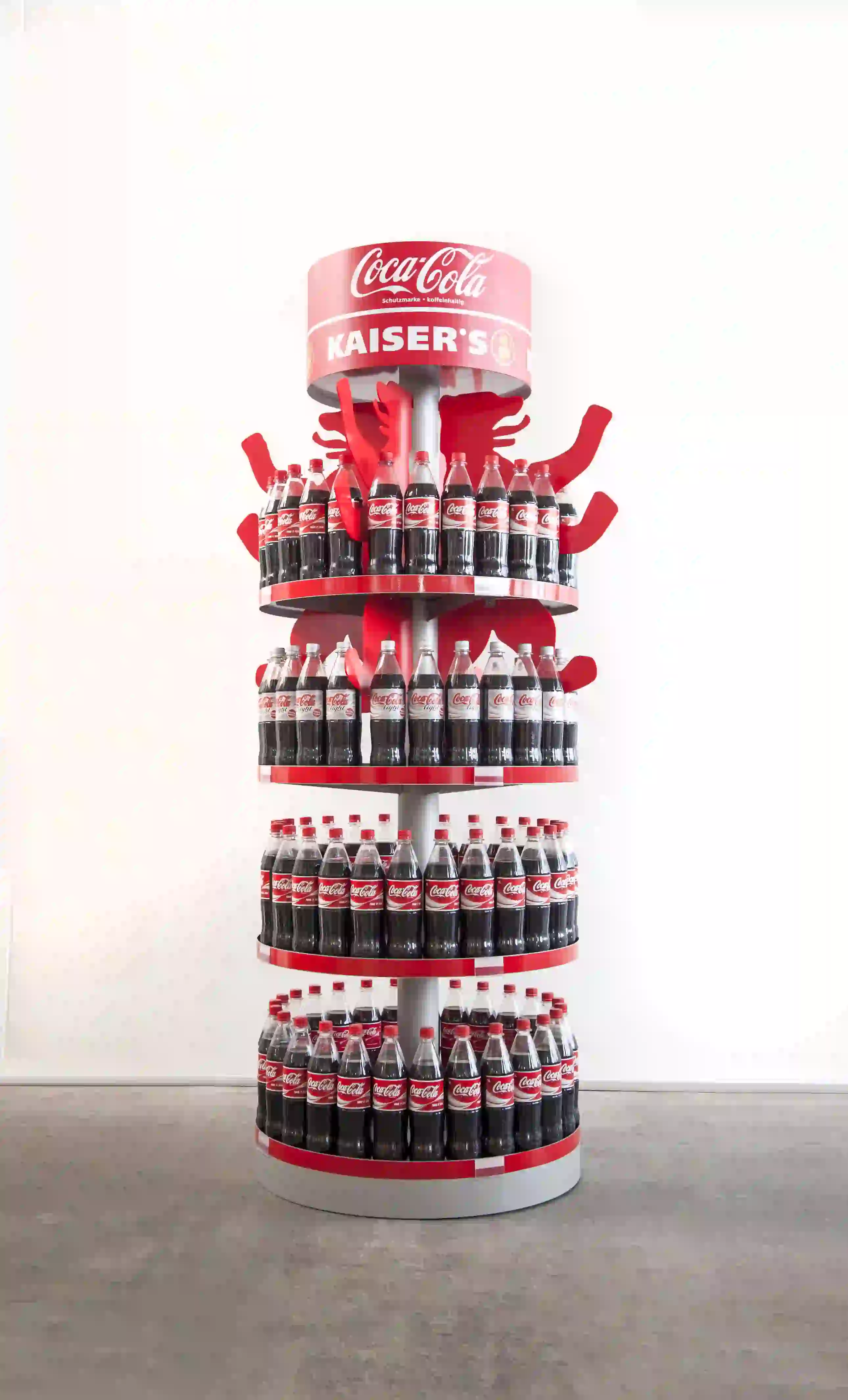 Coca-Cola bottles displayed on red circular stand in retail setting